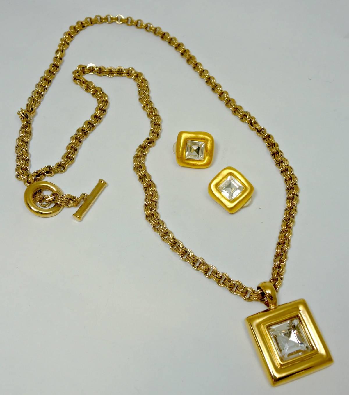 This Givenchy necklace is designed with a pendant that has a large gold tone frame with a square faceted crystal inside. It has a long and heavy rope link chain with a toggle closure. It measures 33” x 1/4”. The pendant measures 1-1/8” x 1-1/8”. 
