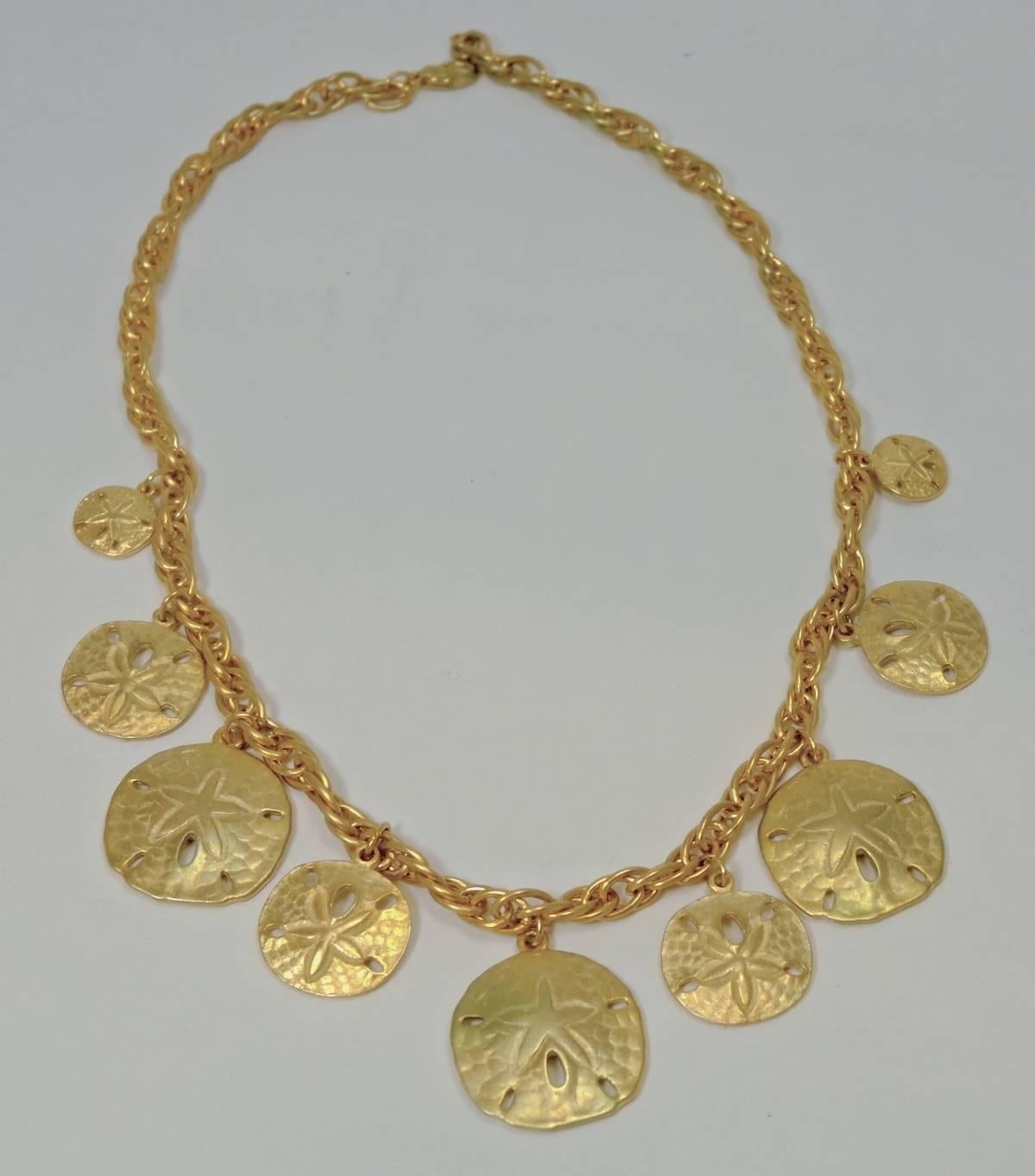 This pretty necklace features nine discs, all designed with a starfish in the center, dangling from a gold tone link chain. This necklace measures 18” x 1/4” and has a lobster clasp. It is in excellent condition.