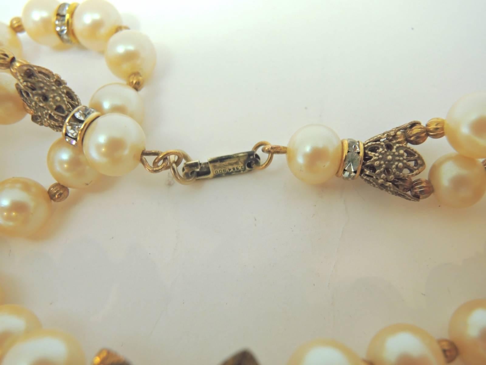 This Miriam Haskell necklace was designed with two strands of faux pearls. There are rondelles and gold tone beads that are used as spacers. This necklace leads to a lovely centerpiece made with three large flowers. All of them have faux seed pearls
