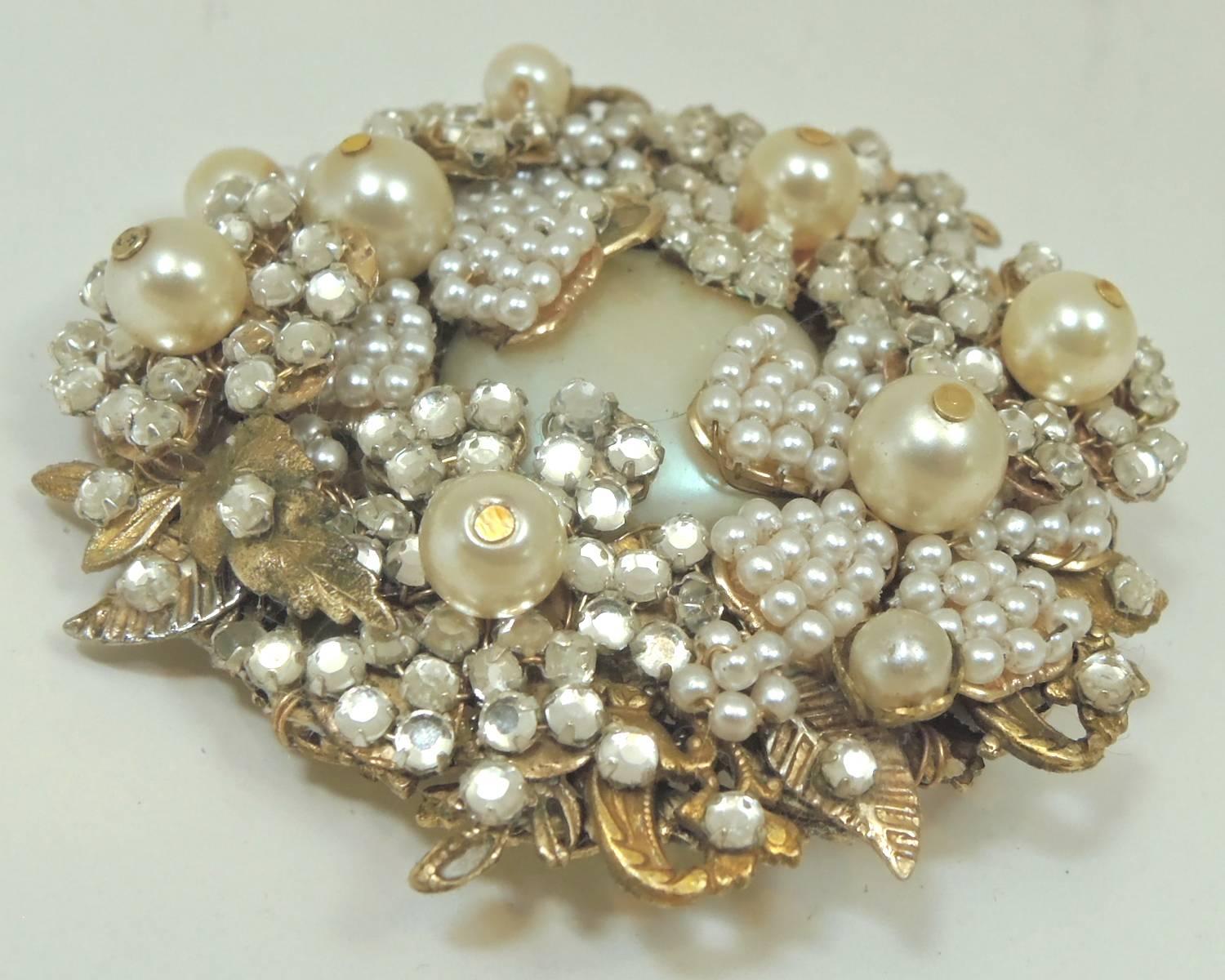 Miriam Haskell is known for her beautiful floral brooches and creative work. This brooch is a fine example. It was designed with flowers all accentuated with rose montee stones and faux seed pearls. There are nine round faux pearls scattered