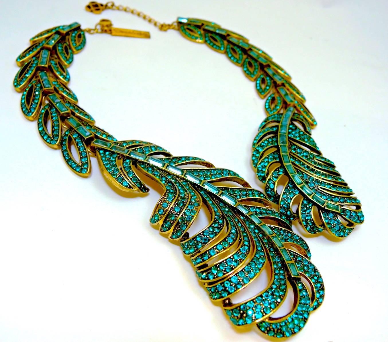 This feather shaped Oscar De La Renta necklace gives these pave set and baguette green crystals a weightless appeal.  It is made in a gold tone setting and measures 19” x 2-1/8” at the widest part.  It has a lobster clasp and is signed “Oscar De la