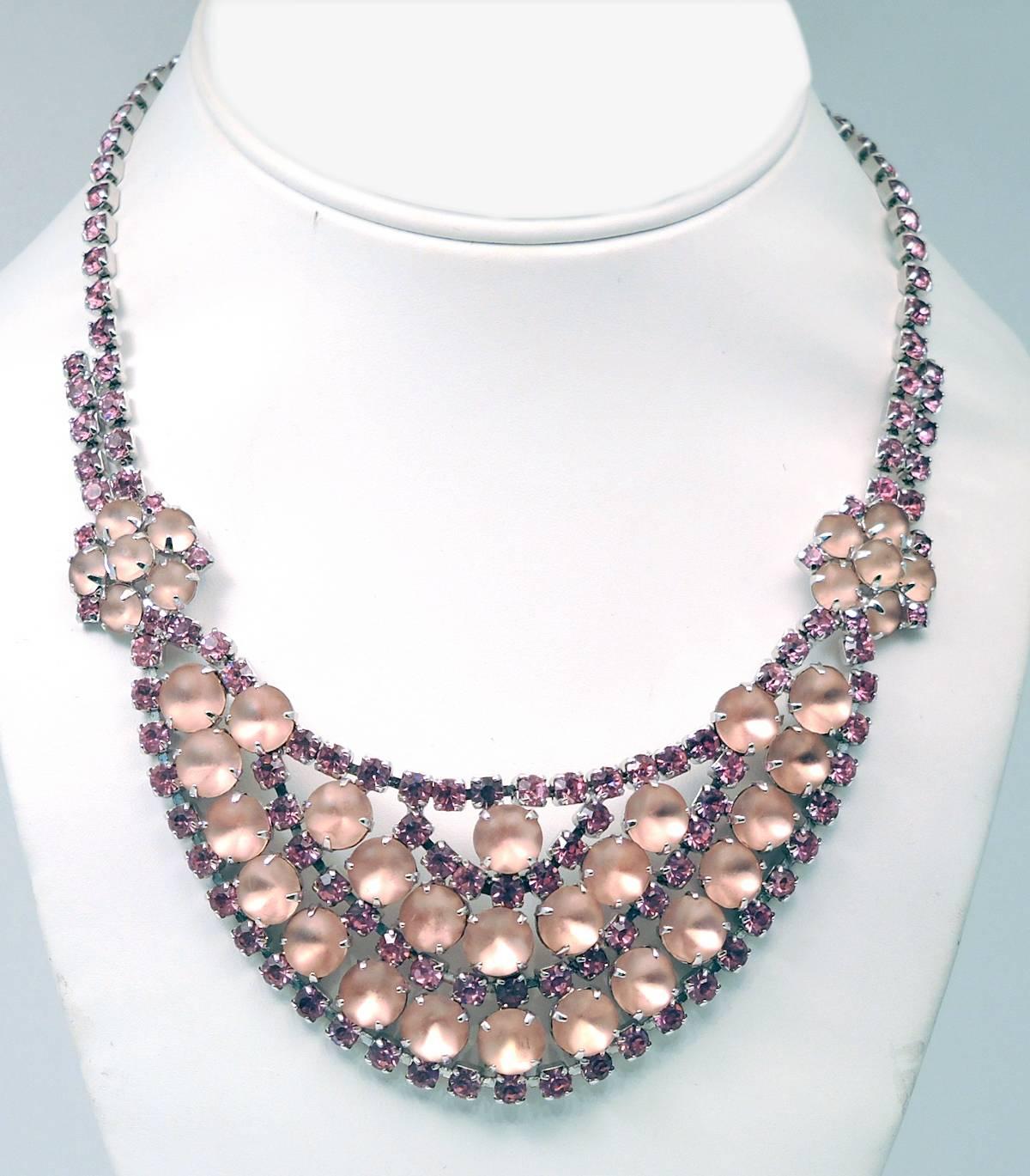 This is a beautiful 1960s pink necklace with an alternating combination of pink large moonstones and dazzling pink rhinestones. It has a hook clasp. This necklace measures 16” x 2” and has a silver tone setting. It is in excellent condition. 