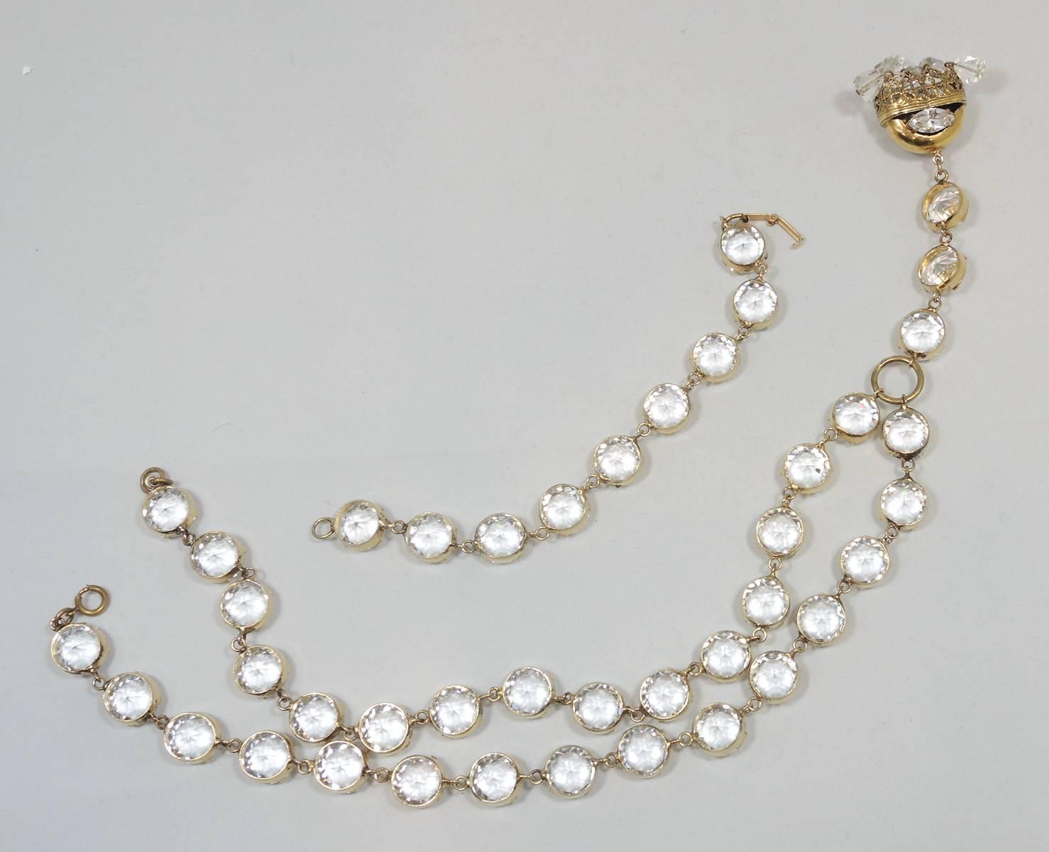 This Deco necklace is rare and will definitely have people looking at you! It has 32 large faceted open back crystals pronged onto gold tone borders. The crystals lead down to an ornate centerpiece that has a marquis crystal on each side and 8