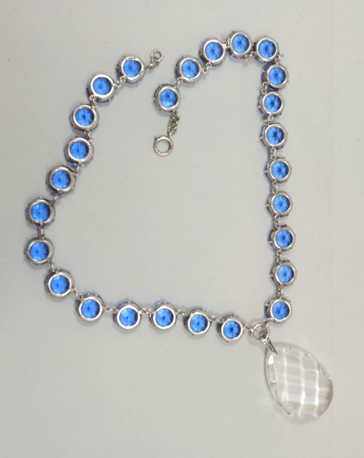 I have never seen this necklace before.  It is different and yet has a classic design.  This necklace has 26 blue faceted and prong set open back crystals. There is a large clear and faceted teardrop crystal at the drop. It has a spring ring clasp