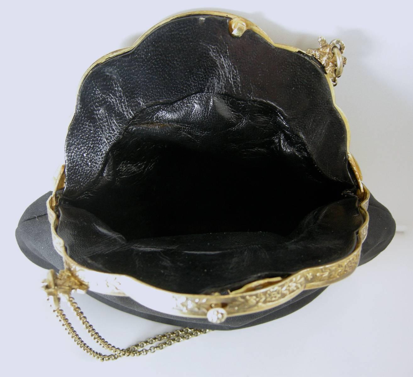 This is a wonderful old 1930s evening bag.  The top frame has an ornate sterling silver with a gold vermeil cherubs design.  There are two chains that are 7” high.   The body of the bag is made of silky cloth material.  The inside is made of black