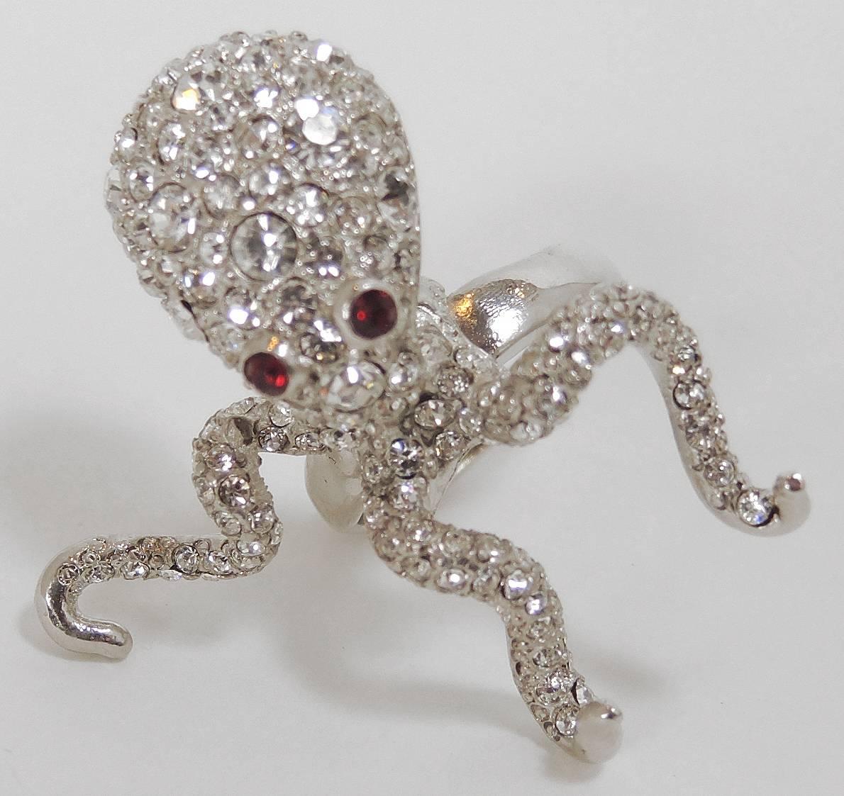 Take your fashion under the sea with this gorgeous silver toned crystal encrusted octopus ring. This octopus has red crystal eyes and there is a hidden inner ring guard that adjusts from sizes 6-7. It is signed “Kenneth Lane” and is in excellent