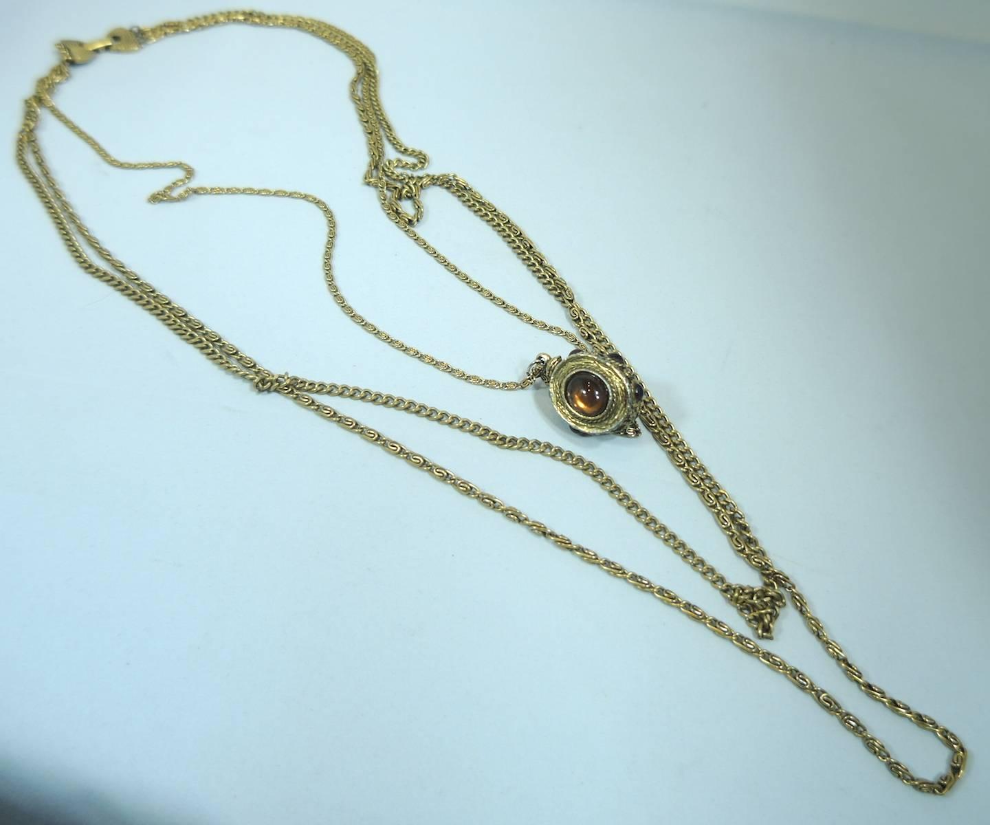 This is a signed Goldette from the 1950s that has 3 chains. The center chain has a faux citrine cabochon set in an intricately designed pendant and has smaller cabochons around it; the longest chain measures 36”. The pendant measures 1-1/4” x