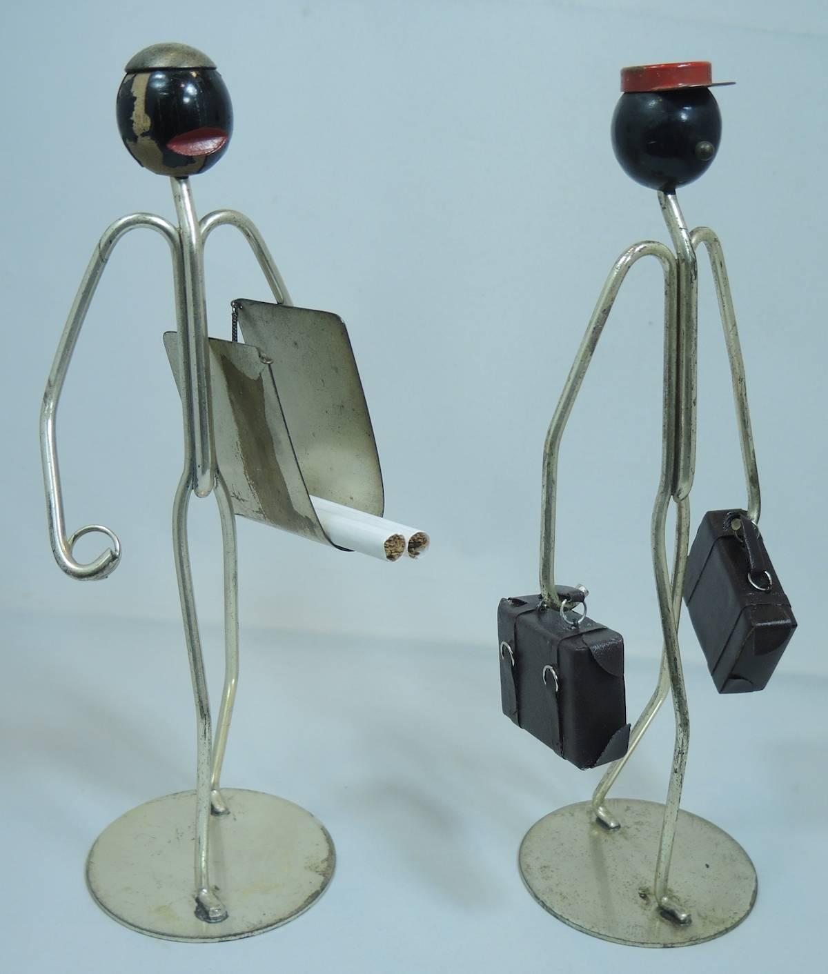 These Art Deco figures are of bellboys and were made in the 1920s by the Napier Jewelry House. They are made of chrome. One of them is holding two suitcases and the other was used to hold cigarettes (now it can business cards). There are signs of