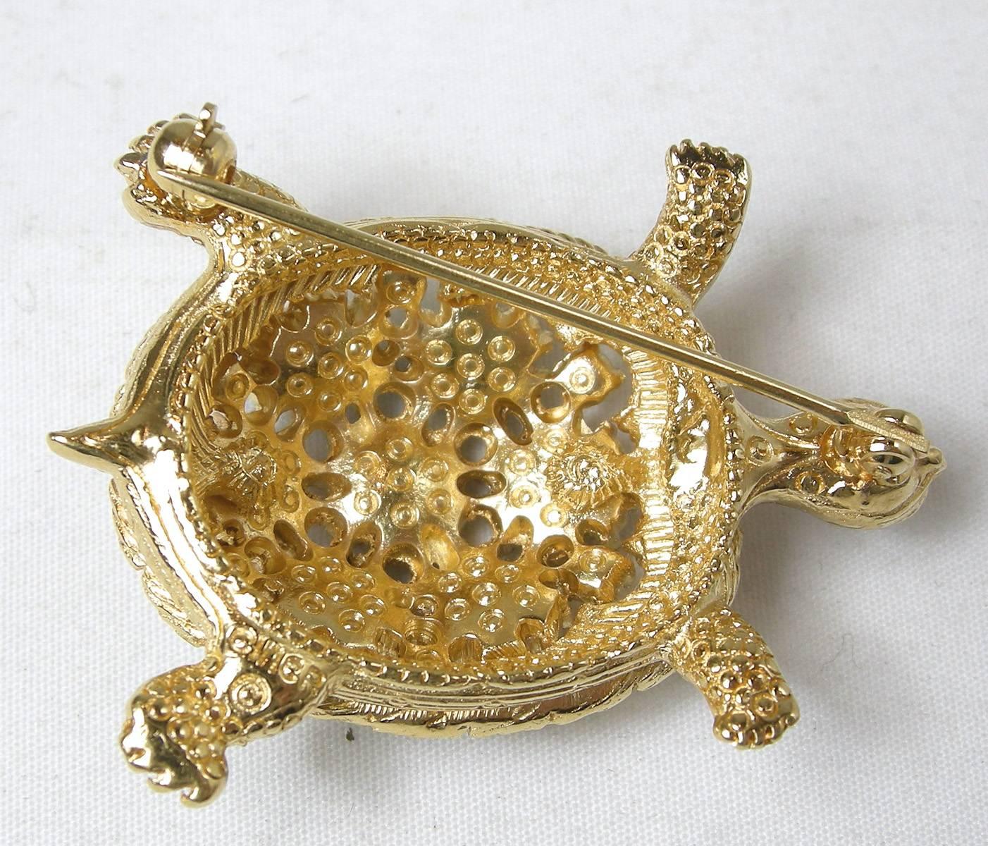 This1960s Ciner turtle brooch is adorable. There are clear rhinestones on his face and feet, with faux rubies, emeralds and sapphires on his back. It is made in a gold tone setting and measures 1-1/2” x 1-1/4”. It is in a gold tone setting and is