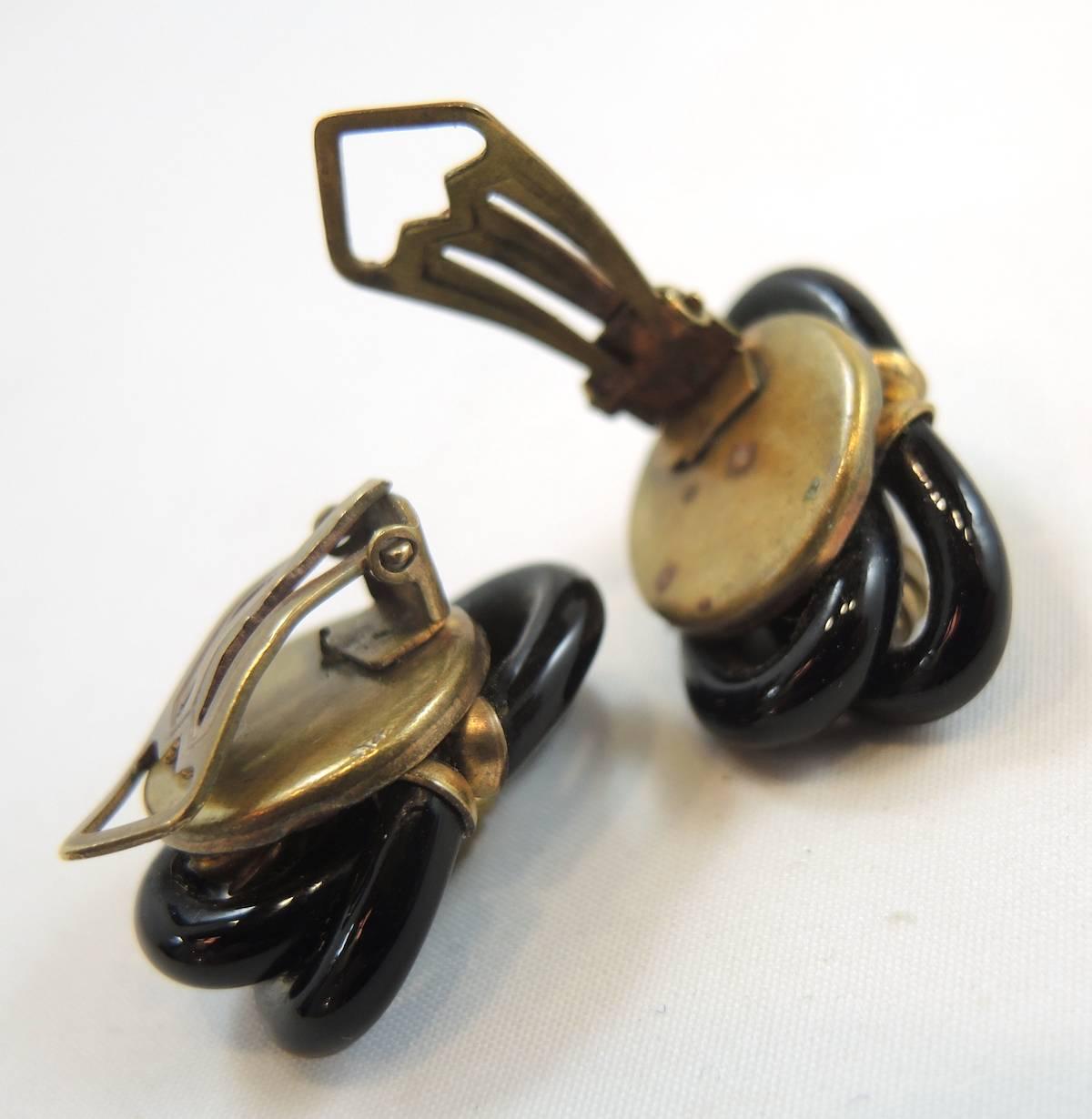 These amazing and rare earrings were designed by the famous Archimede Seguso for Chanel in the 1950s. They are designed with interlocking black glass and the glass design became an icon collectible. The center has a curved and domed shaped tube.