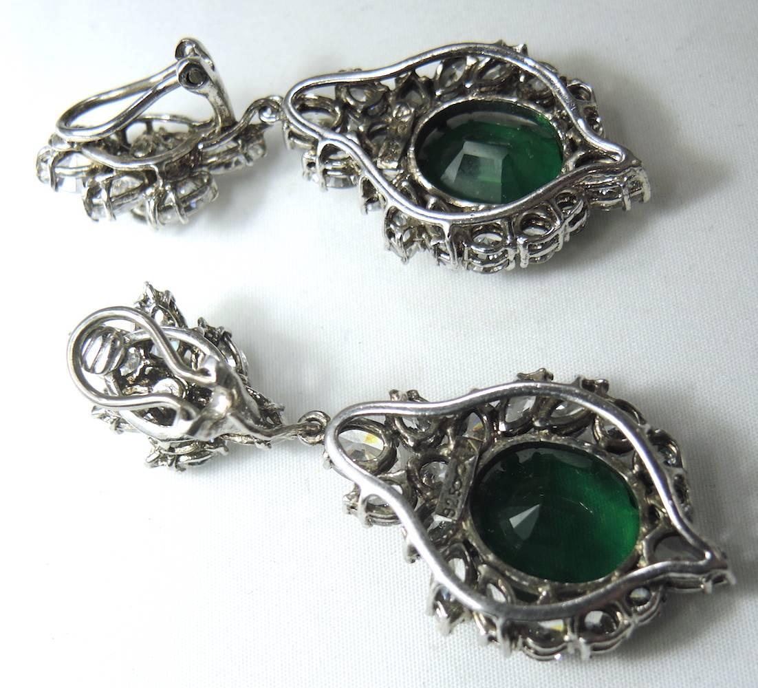 These couture elegantly made statement clip earrings are perfect for any special occasion. They are made with a cluster of brilliant clear crystals on top. The bottom dangles with a large round emerald green crystal in the center and surrounded with