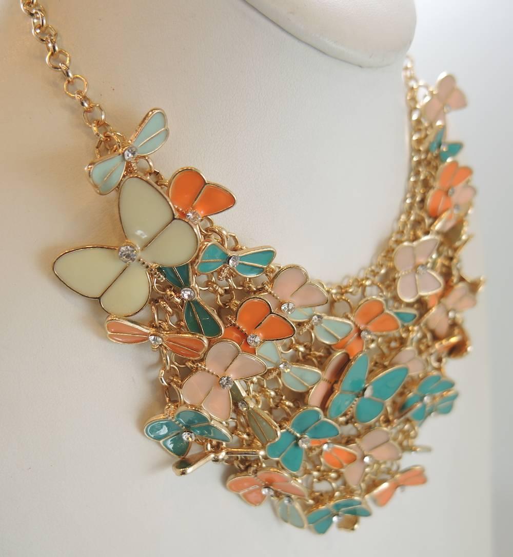 This fun necklace has coral, cream and mint enameled butterflies that gather at the base of your neckline. These butterflies are accentuated with a beautiful rhinestone center. It has a lobster clasp and measures 21”, all set in a gold tone metal
