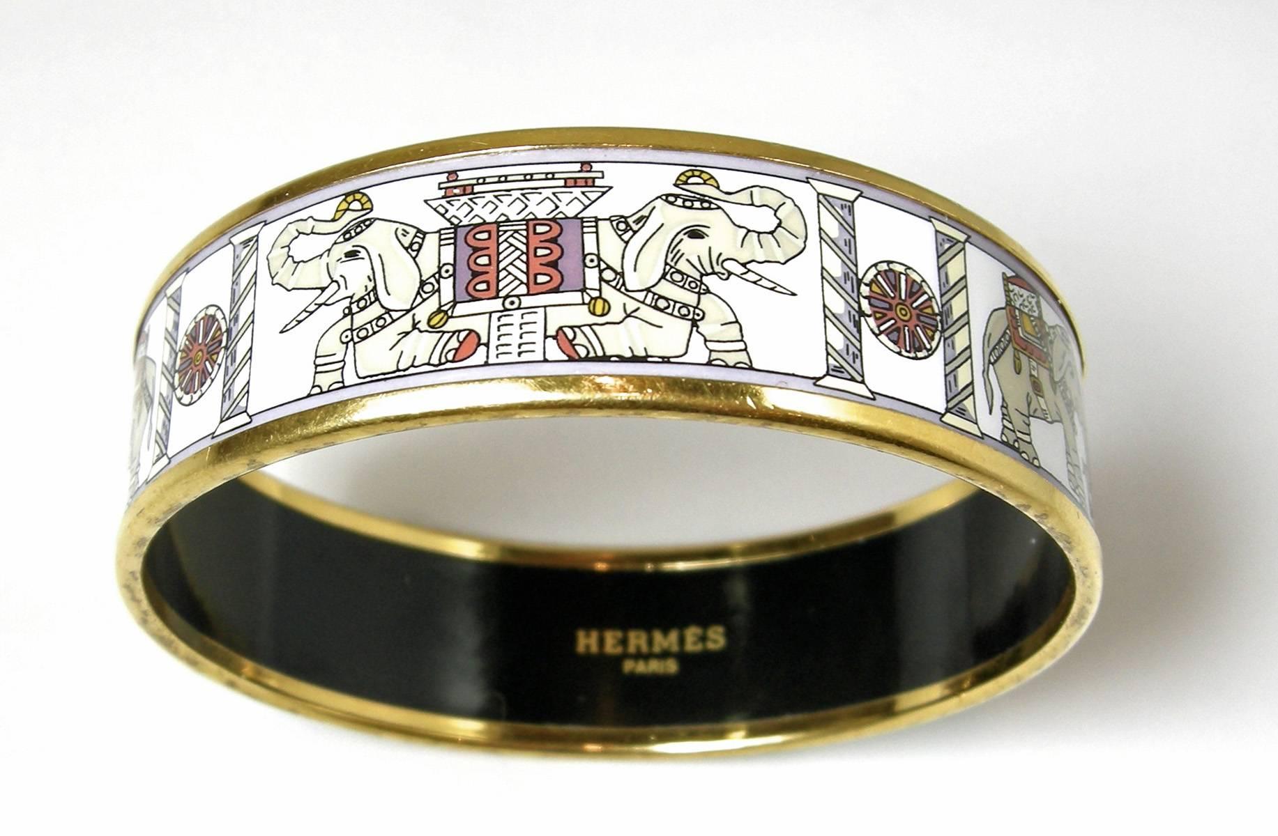 This is an authentic, very collectible, vintage Hermes white enamel printed elephant bracelet. This stunning bracelet has a black inner face with the exterior featuring an outside gold tone rim. It has an elaborately enameled Asian elephant motif.