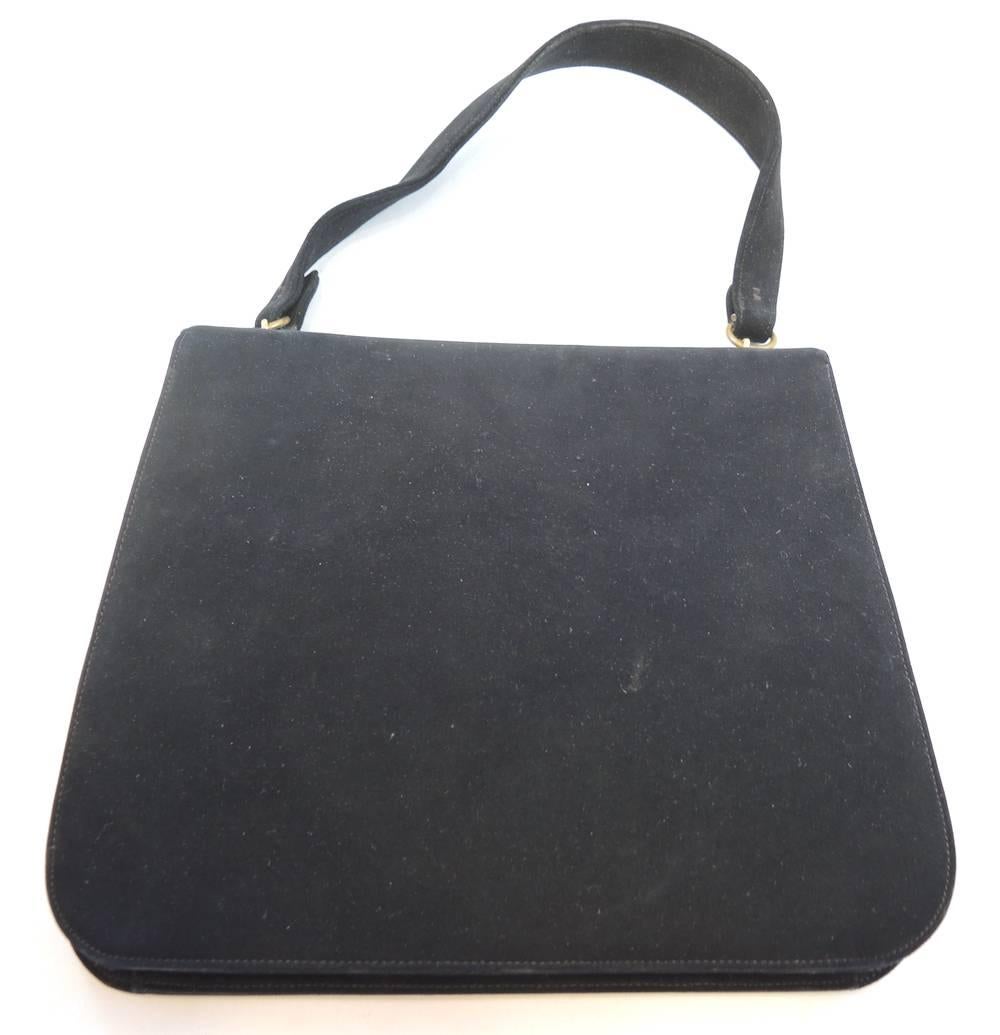 This handbag has an exterior that is made of black suede that is intact and does not release black dye on your hand.  It is perfect.  The flap has a gold tone hardware made with black enamel. The latch style clasp is mounted with a thick textured