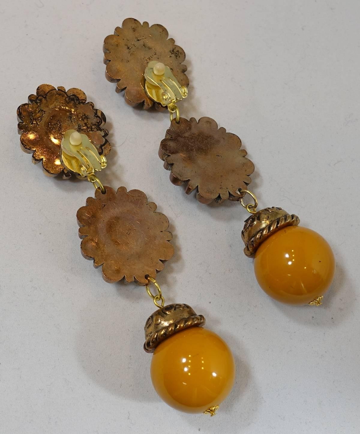These vintage clip earrings are segmented in 3 sections to dangle downward. The first two have an oval butterscotch enamel stone in the center surrounded by a copper color ribbed border.  The bottom has a butterscotch enamel ball connected to a