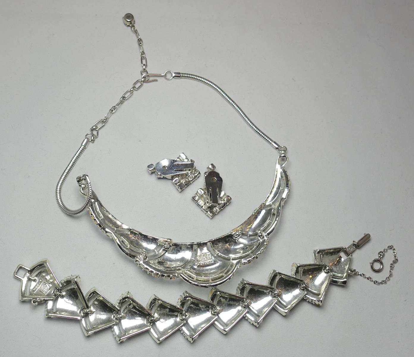 This is a beautiful vintage Coro set from the 1950s. The necklace is a choker with an articulated curved shape, measuring 15” x 1-1/3” at the widest part. It has a hook clasp. It has rectangular, bell-shaped textured panels. Each panel is