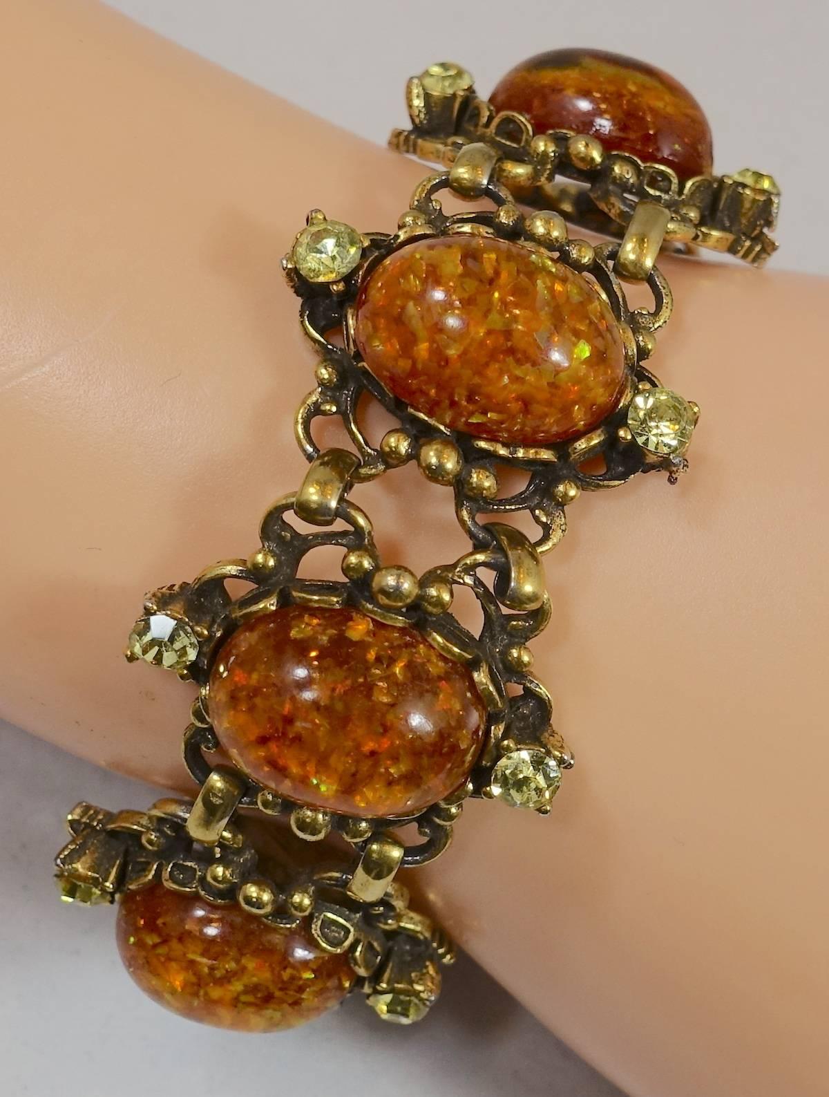 This is a great bracelet by Coro.  It has opaline stones with citrine glass cabochon stones. Each stone has a round yellow crystal on top and the bottom. It has a fold over clasp and is designed in an open work gold tone setting. It measures 7” x