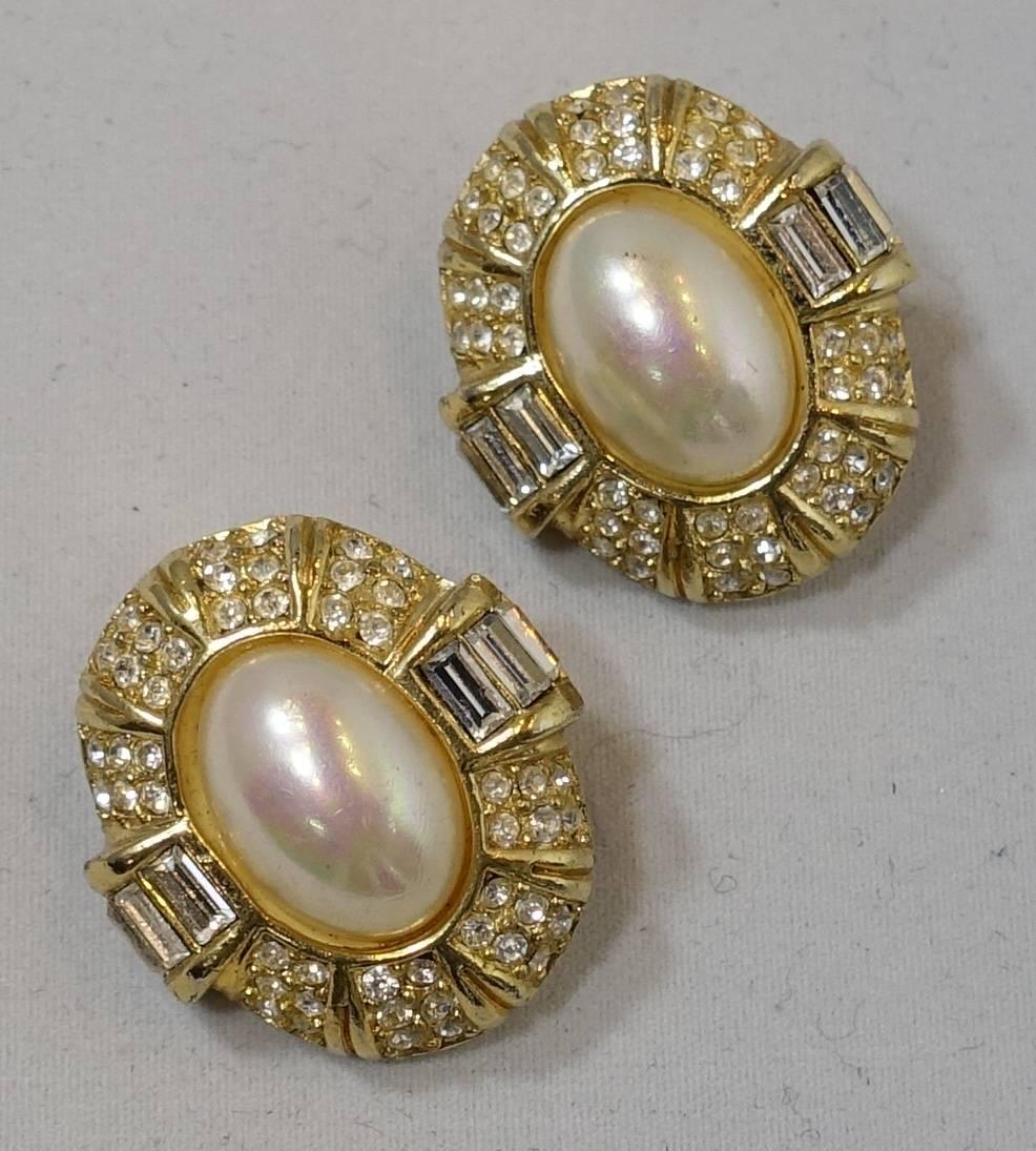 These vintage earrings by Christian Dior have a classic and elegant style. It has a large oval faux pearl center surrounded by crystals with crystal baguettes on the side. They are in a gold tone setting and measure 1” x 1”. They are signed