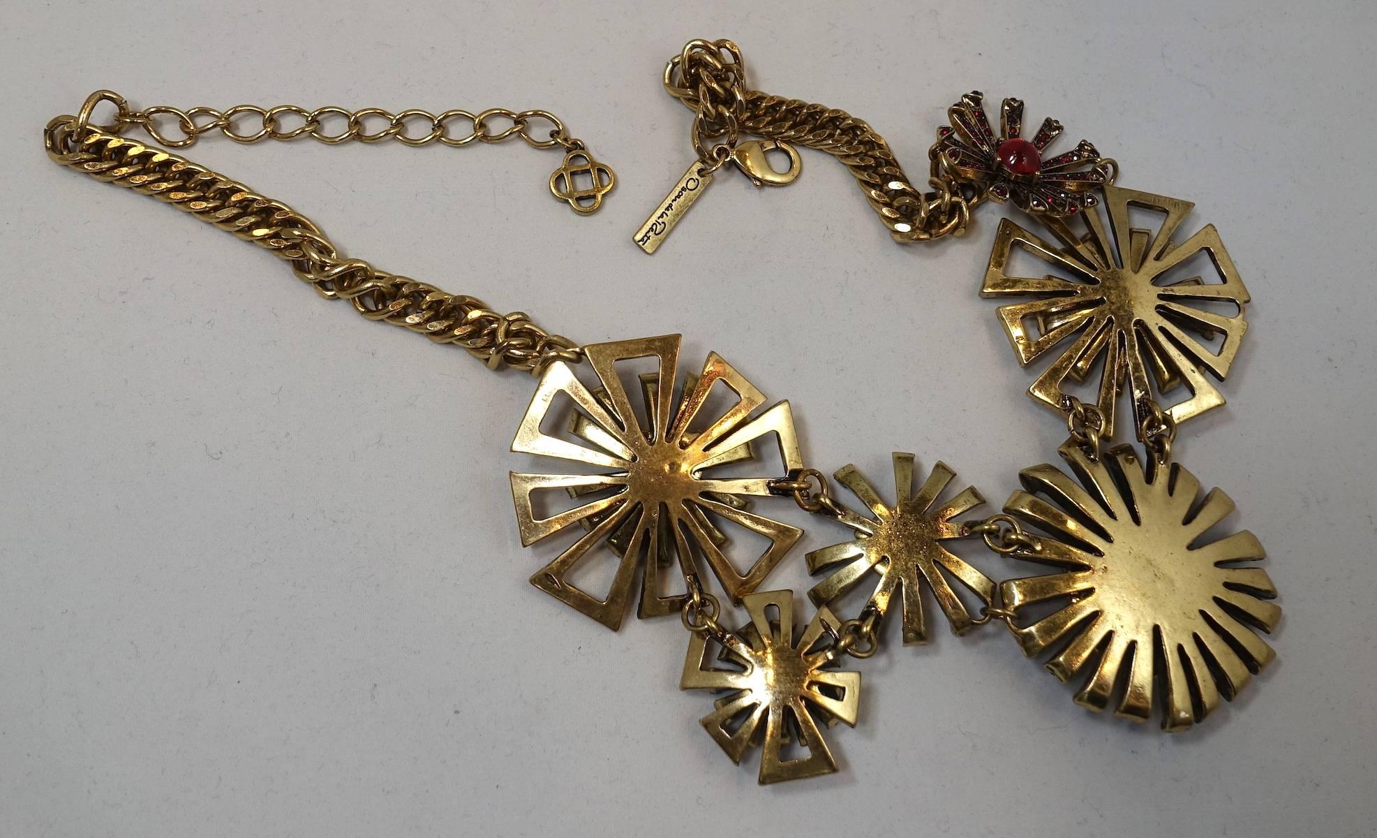 This Oscar De La Renta necklace has six abstract starbursts with rose color crystals. It’s in a gold tone setting and has a lobster clasp. It is connected with a heavy chain and then an open link chain to make sizing adjustable.  The centerpiece is