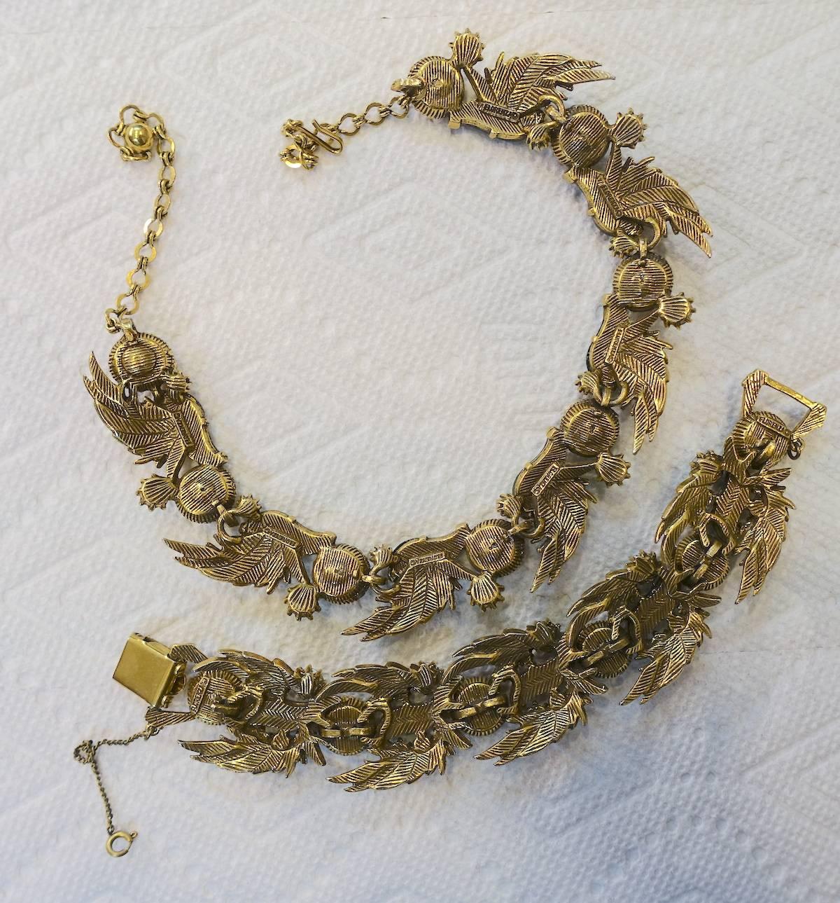 This vintage 1960s Florenza set features aurora borealis and citrine faceted rhinestones in a gold tone setting. The necklace has a hook clasp and measures 16” x 1”. The bracelet measures 7” x 1” with a fold over clasp with a safety chain. This set