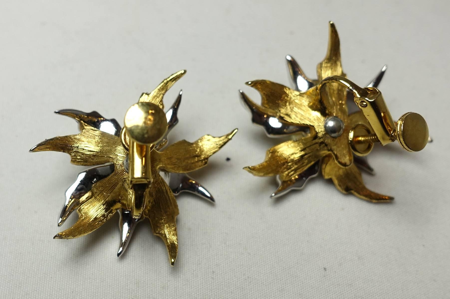 These vintage 1950s Jomaz earrings feature a floral design with faux pearls and clear rhinestone accents in a gold and silver tone mixed-metal setting. These clip earrings measure 1” x 1” are signed “Jomaz”.  They are in excellent condition.