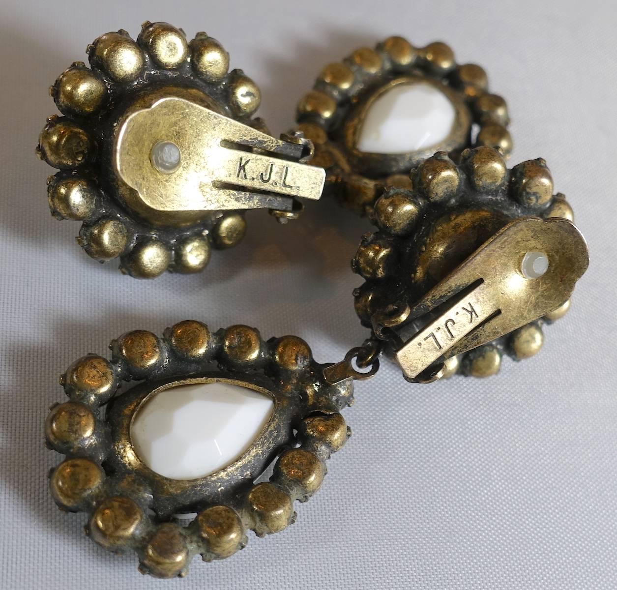 These rare 1960s signed K.J.L. earrings feature white cabochon stones with crystal accents in a brass tone setting.  These clip earrings measure 2” x 1”, are signed “K.J.L.” and are in excellent condition.