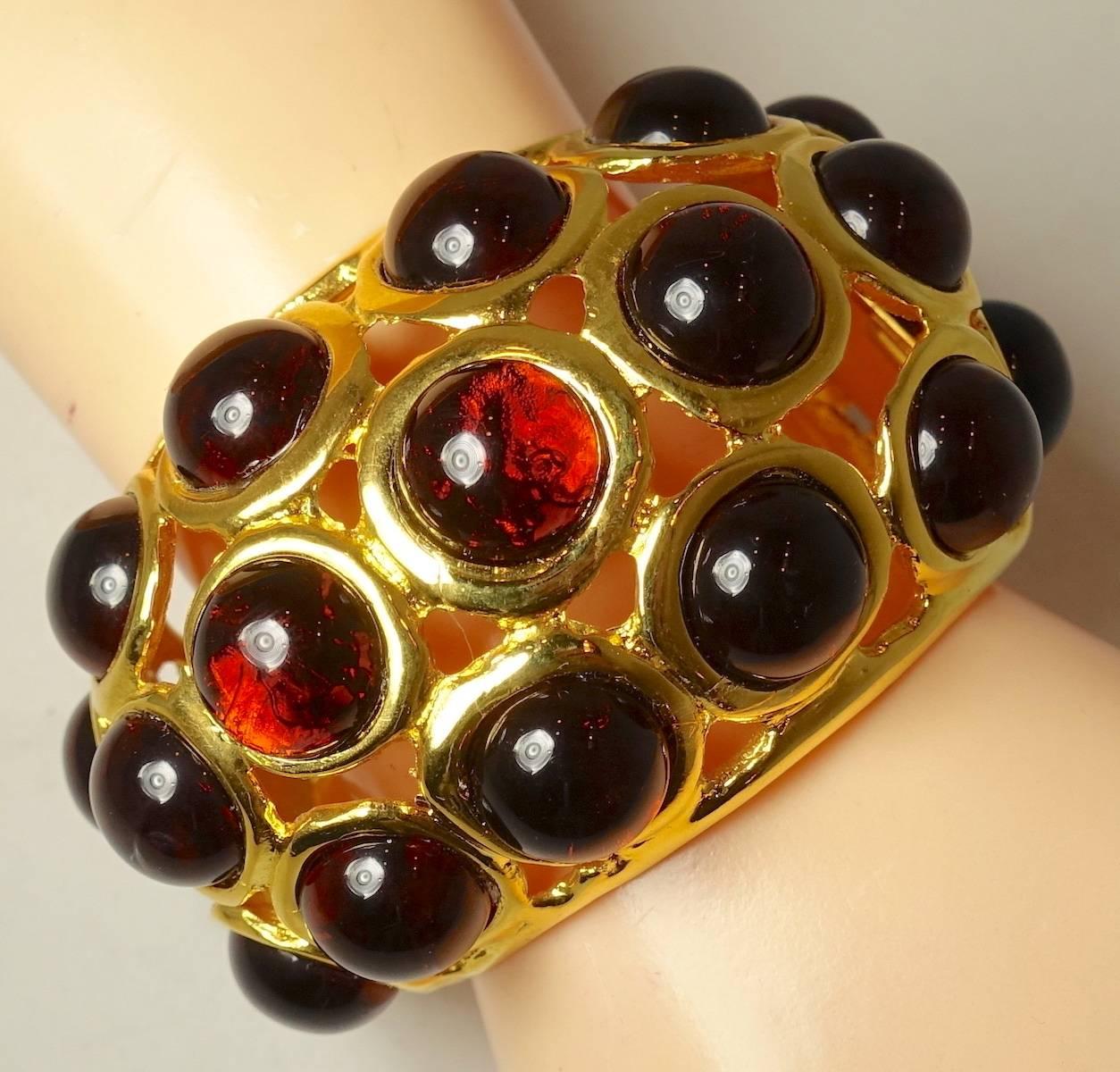 WOW!  We have twin bracelets from Kenneth Lane. Each one features 3 rows of round red glass cabochon stones with a hinged flap on one side. This cuff bracelet measures 9” x 2-1/2” and is signed “Kenneth Lane”.  It is in excellent condition.  We are