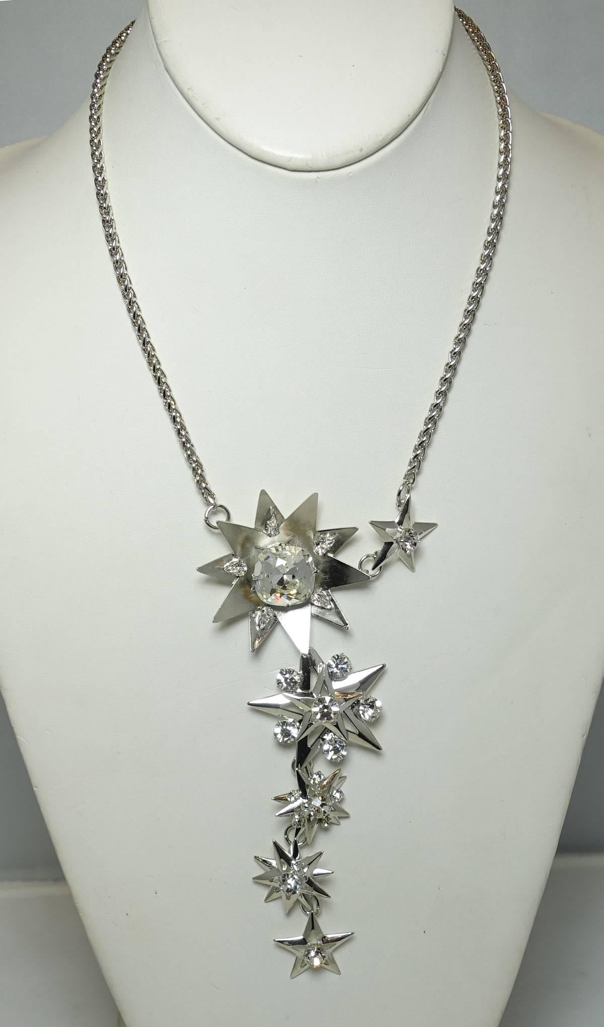 This one-of-a-kind necklace by Robert Sorrell features a floral centerpiece with large crystal accent. There is a star next to it and the necklace has a drop with 4 more stars. All stars are decorated with faceted crystals. This necklace was