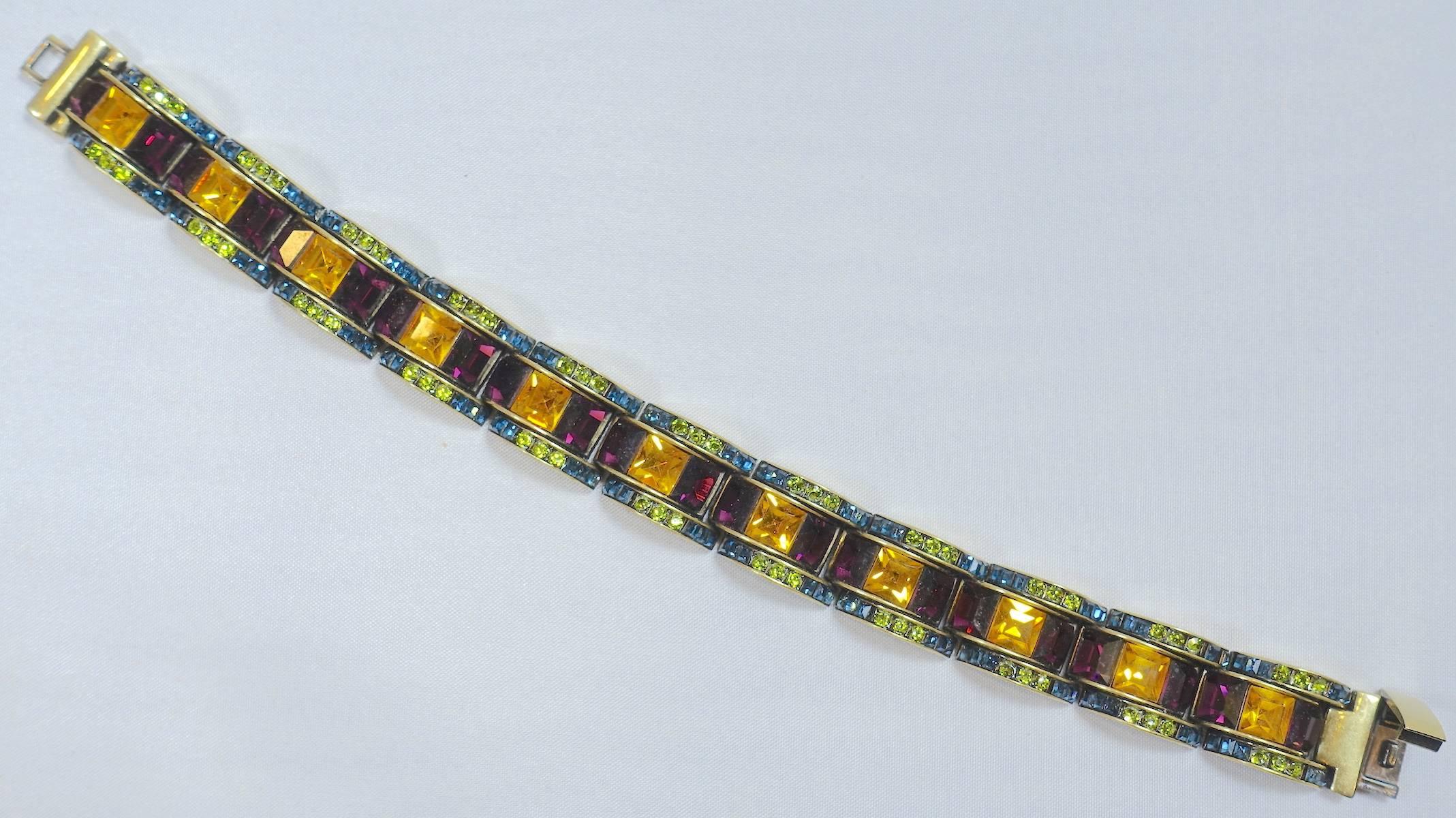 This is a rare deco multicolor stone heavy brass bracelet. The larger stones are purple and citrine accented by smaller green and blue stones that are set in a scalloped line. The bracelet is a rare find and is an elegant showstopper! In excellent