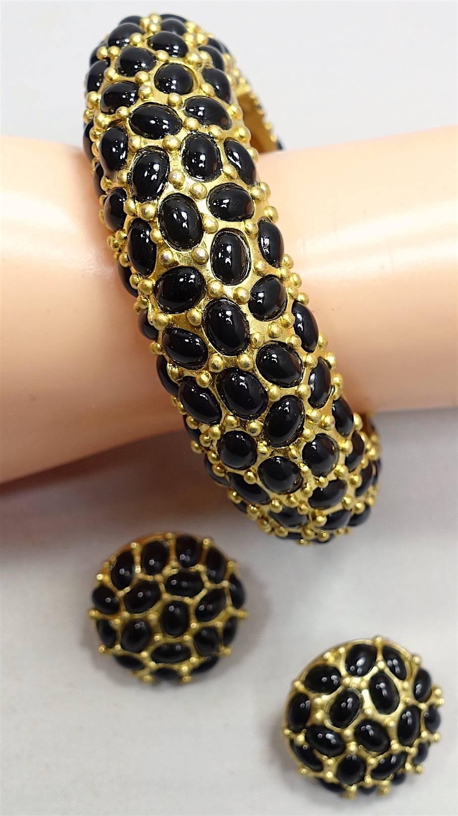 This Kenneth Lane set goes with anything and features black cabochon stones in a gold tone setting. The clamper bracelet measures 9” x 1”; the clip earrings measure 1” x 1”. This set is signed “Kenneth Lane” and is in excellent condition.