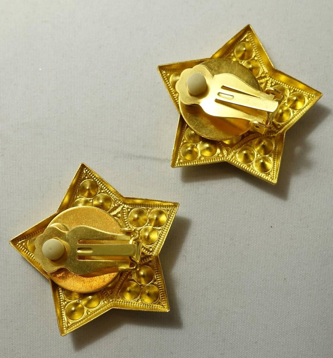This vintage signed Kirks Folly earrings feature a star design with faceted Aurora Borealis in a heavily etched gold tone setting.  These clip earrings measure 1-1/2” across and are signed “Kirks Folly”.  They are in excellent condition