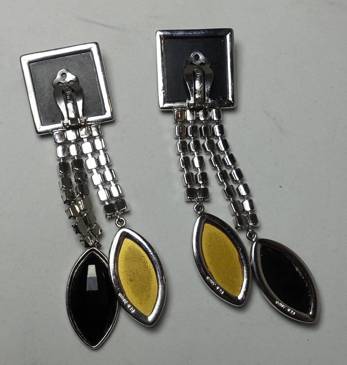 These long drop earrings feature a deco design with a black resin squares at the top. Two rows of clear rhinestones lead down to a black and clear teardrops. These clip earrings measure 4-3/8” x 1-1/4” and are in excellent condition.