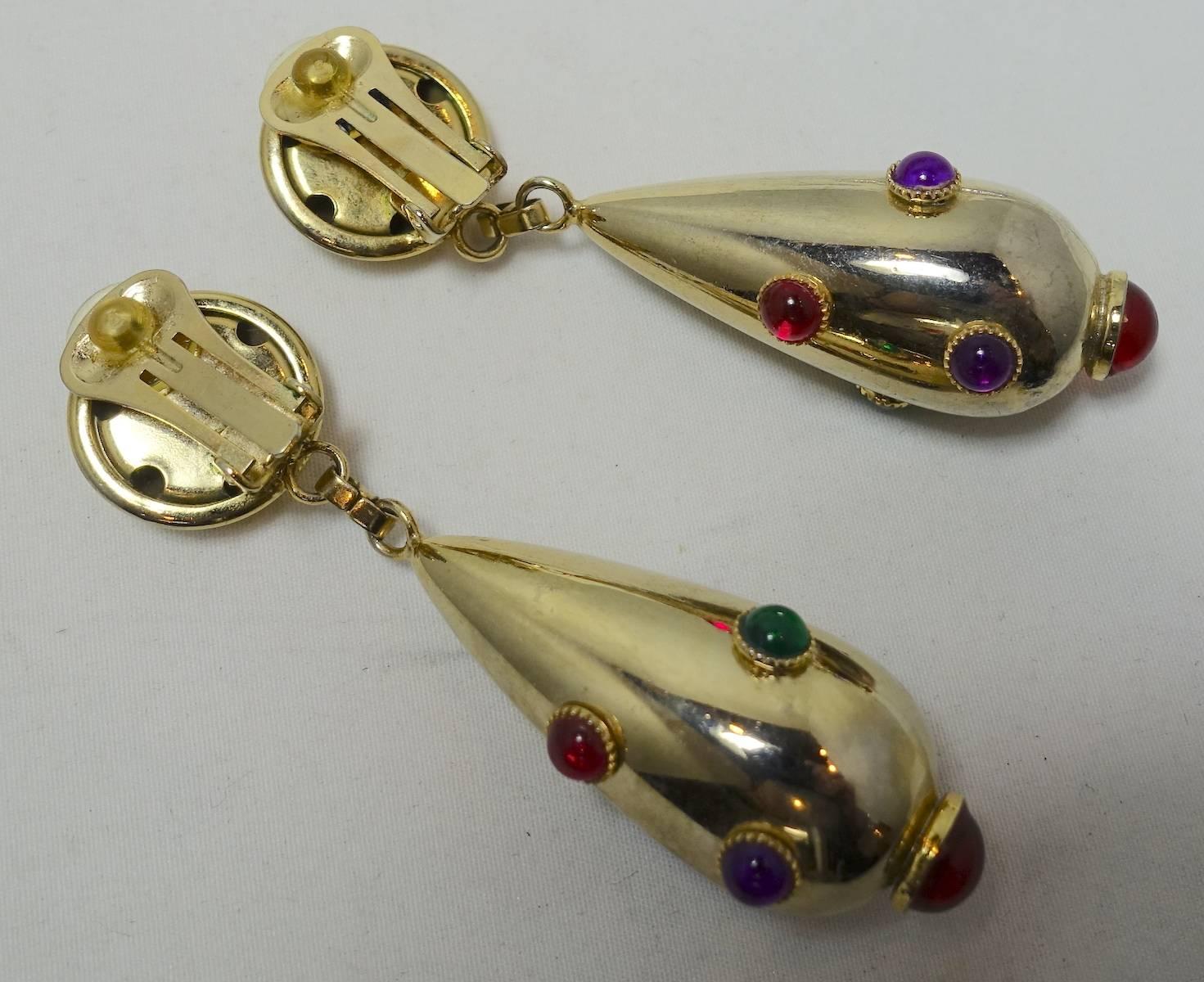 These vintage 1970s drop earrings are designed with cabochon red, green, blue and amethyst crystals in a gold-tone setting.  These clip earrings measure 3” x 1” and are in excellent condition.