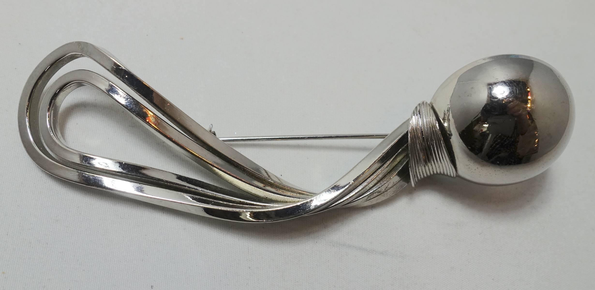 This vintage 1960s brooch features and abstract modernist design in a silver tone setting. In excellent condition, this brooch measures 4” x 1” and has a turn closure.