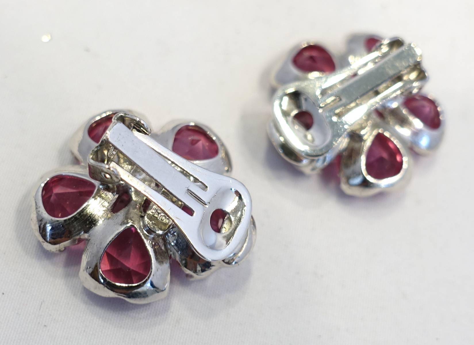 These earrings feature a floral design with hot pink crystal with clear crystal accents in a silver tone setting. These clip earrings measure 1” across and are signed “Replica Made in Italy”.  They are in excellent condition.