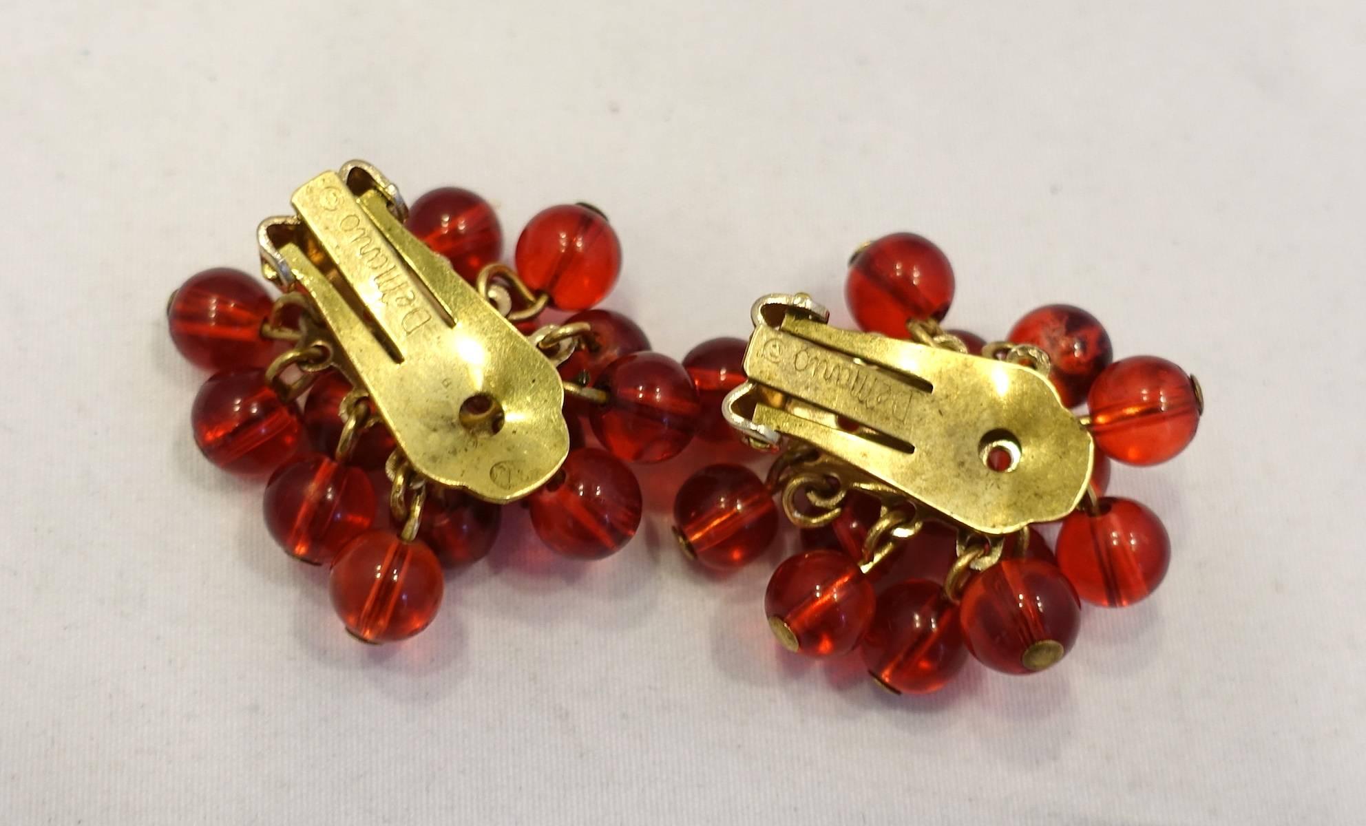 These vintage signed DeMario earrings are designed with red glass beads in a gold tone setting.  These clip earrings measure 1” x 1” and are signed “DeMario”.  They are in excellent condition.