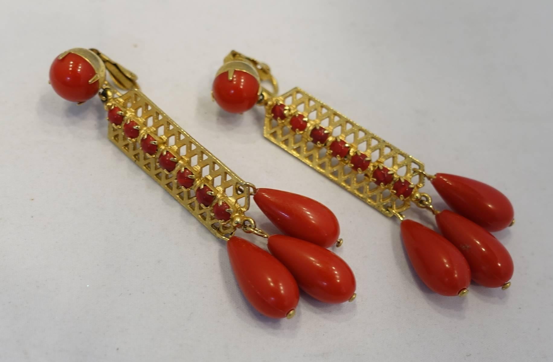 These vintage 1960s dangling earrings feature a round red bead on top with a long gold tone center with red beads in the center.  At the bottom are three red beads hanging down. These clip earrings measure 3-1/2” x 1” and are in excellent condition.