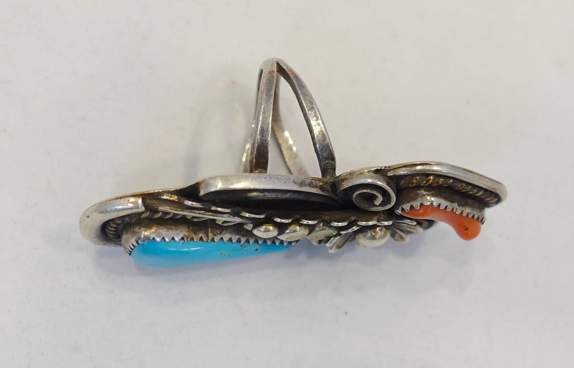 This vintage ring features turquoise & coral stones in a sterling silver setting.  This ring measures 2-1/4” long x 1” wide and is a size 7. It is in excellent condition.