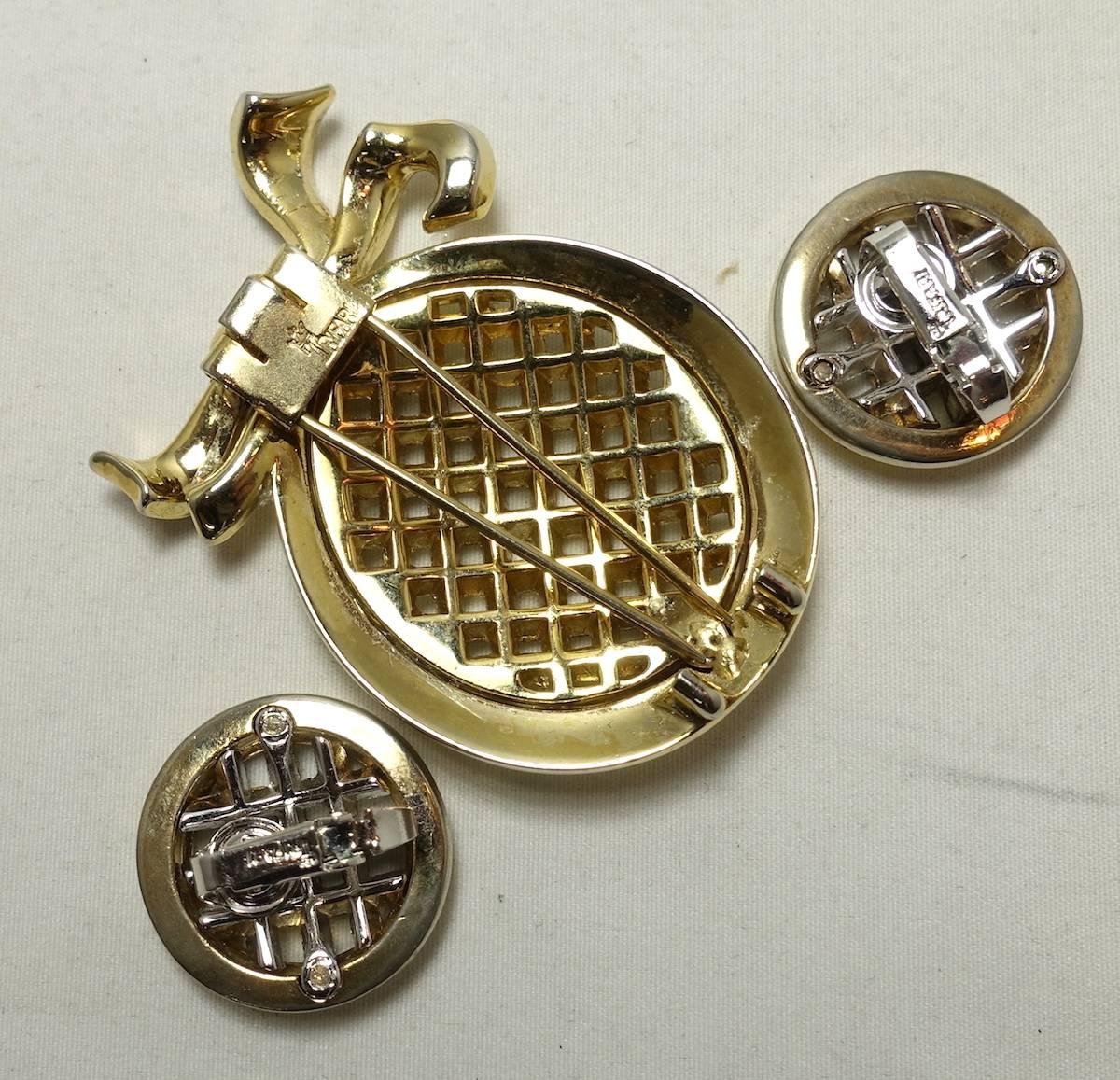 This Trifari 1960’s set includes a brooch with a basket weave center made with clear rhinestone baguettes in a mixed-metal setting. It has bow on top and measures 2-1/2” x 1-1/2”. The matching clip earrings measure 1” x 1”. This set is signed