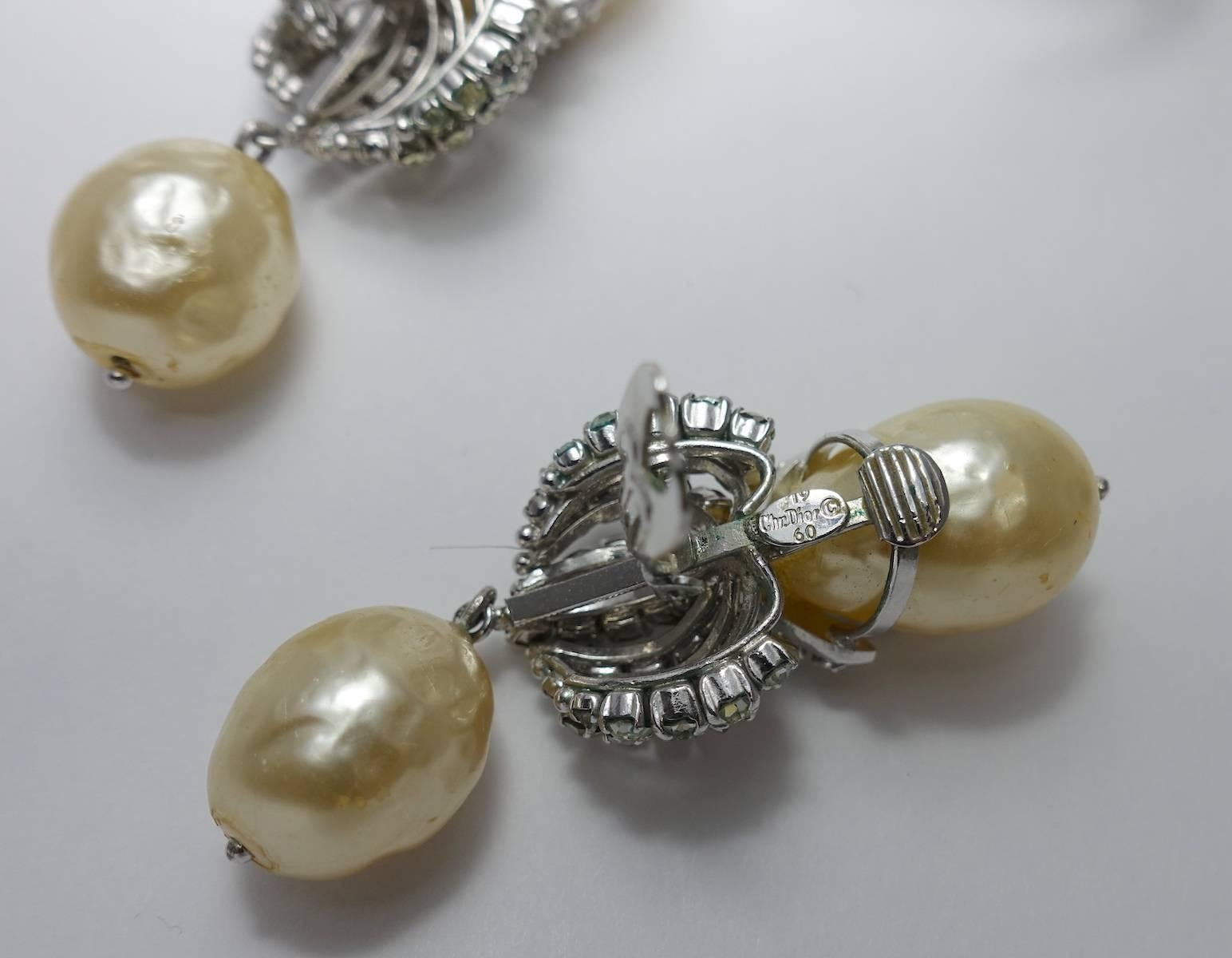 This is a rare, 1960s vintage signed Christian Dior brooch & earrings featuring faux pearls with crystals in a rhodium silver tone setting.  The brooch measures 3-3/8” x 2-3/8” with a turn closure. The matching clip earrings are 2-5/8” x 7/8”.