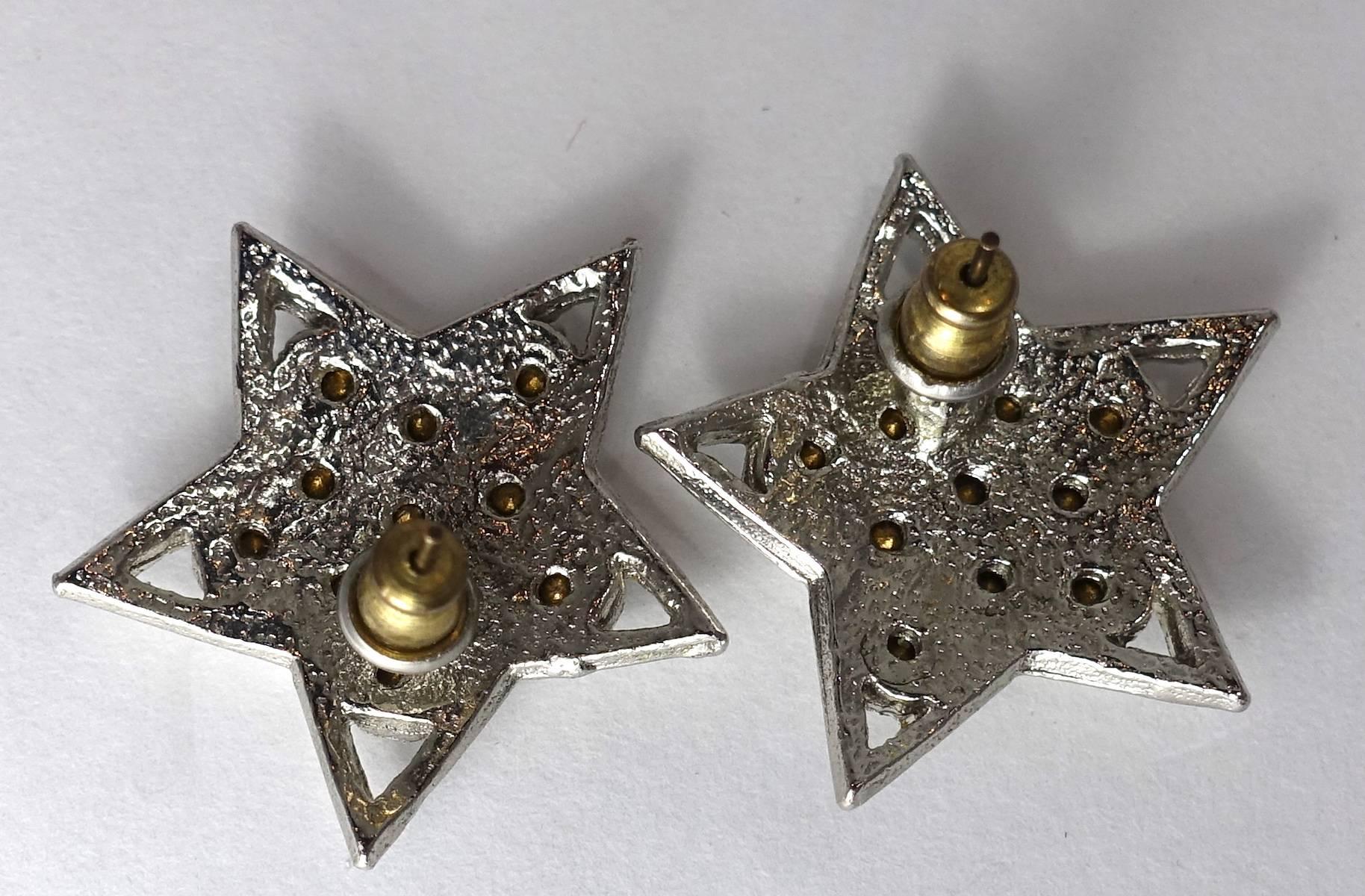 These vintage 1960s earrings feature clear crystals in a rhodium silver tone setting.  These pierced earrings measure 1” across and are in excellent condition.