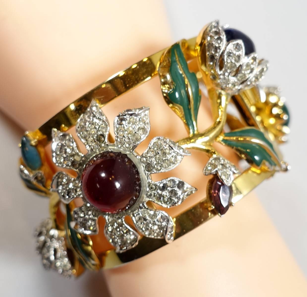 This is the famous Carmen Miranda “Camelia” Coro book piece bracelet featured in the 1948 movie “A Date with Judy”. This dazzling hinged bracelet features an open work floral design with a pattern of Camellia blossoms, multi-colored poured glass