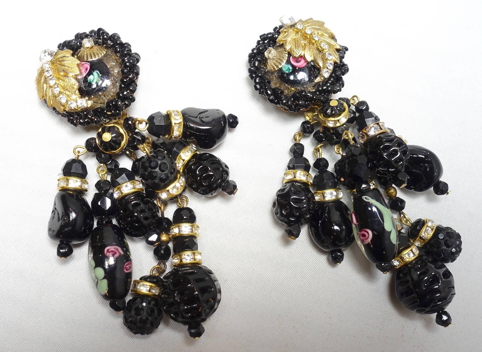 These vintage signed DeMario earrings feature Murano style molded glass beads with a floral design, black beads and crystal rhondells in a gold tone setting.  These clip earrings measure 3-1/4” x 1-1/4” and are signed “DeMario”.  They are in