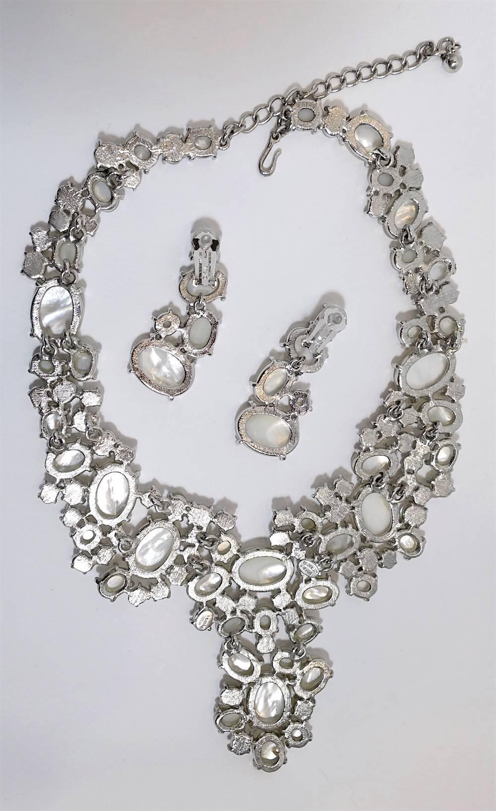 This Kenneth Jay Lane necklace & earrings feature faux “mother-of-pearl” cabochons in a nickel-free silver-plated base metal setting.  The necklace measures 20” with a 3-1/2” front drop and has a spring closure.  The matching clip earrings are