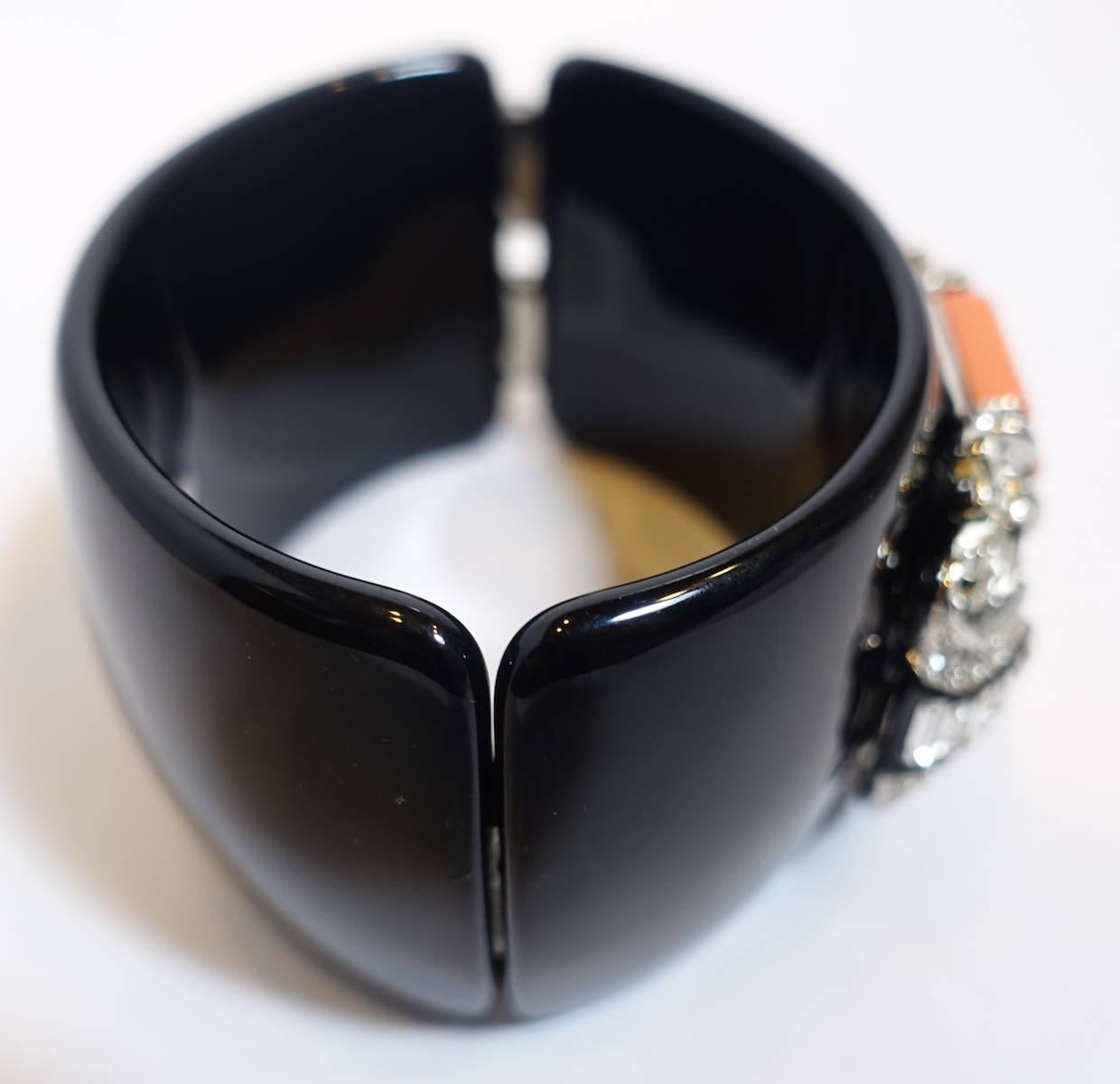 This signed Kenneth Jay Lane deco style clamper bracelet features faux coral rods with crystal accents on a black enameled setting.  This clamper bracelet has spring-closure and it measures 6-3/4” x 1-3/4”.  It is signed “Kenneth Lane” and is in