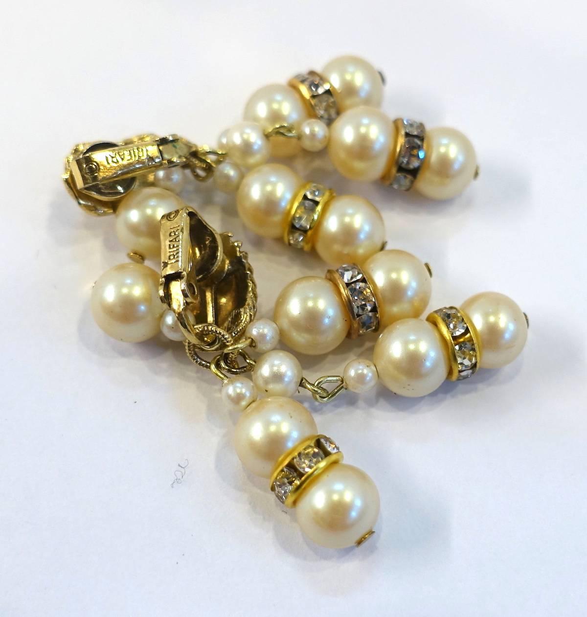 These vintage signed Trifari earrings feature faux pearls with rhondells spacers in a gold-plated base metal setting.  These clip earrings measure 2” x approx. 1” and are signed “Trifari”.  They are in excellent condition.
