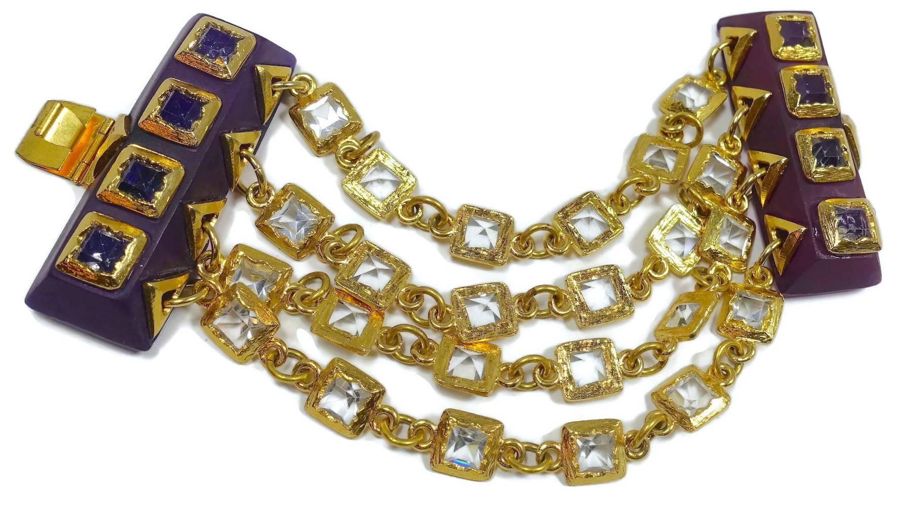 This vintage unusual 1970s bracelet features 4 strands of clear crystals, joined at each end by a purple wood closure with amethyst crystal accents, all in a gold-plated base metal setting.  This bracelet measures 7-1/2” x 2-1/2” with a slide-in