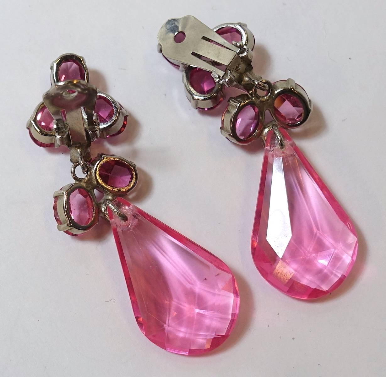 These vintage earrings feature a pink Lucite drop with pink crystal accents in a silver-plated base metal setting.  These clip earrings measure 2-3/4” x 3/4” and are in excellent condition.