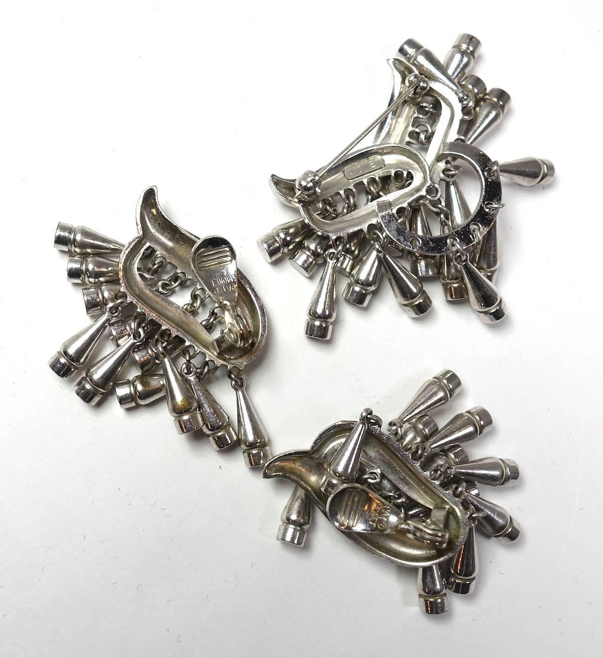 This vintage signed Monet set features multiple bottle-shaped drops in a silver-plated base metal setting.  The brooch measures 1-1/2” x 1-1/4”. The matching clip earrings are 2” x 1”.  This vintage set is signed “Monet” and is in excellent