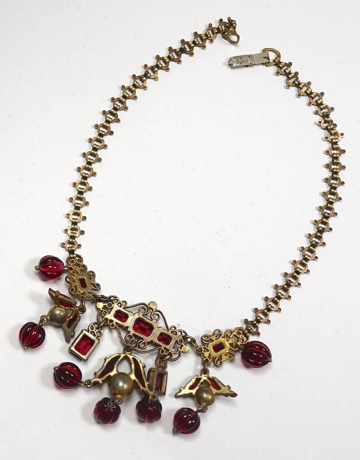 This deco vintage 1930s French necklace has a book chain necklace leading down to faux pearls and red carved glass beads in a gold-plated base metal setting.  In excellent condition, this necklace measures 14-1/2” with a fold-over clasp and the